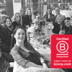 A black and white photograph of the mark-making* team seated together at a restaurant table during their Christmas party, smiling and in good spirits. The Certified B Corporation logo appears in the bottom right of the image.